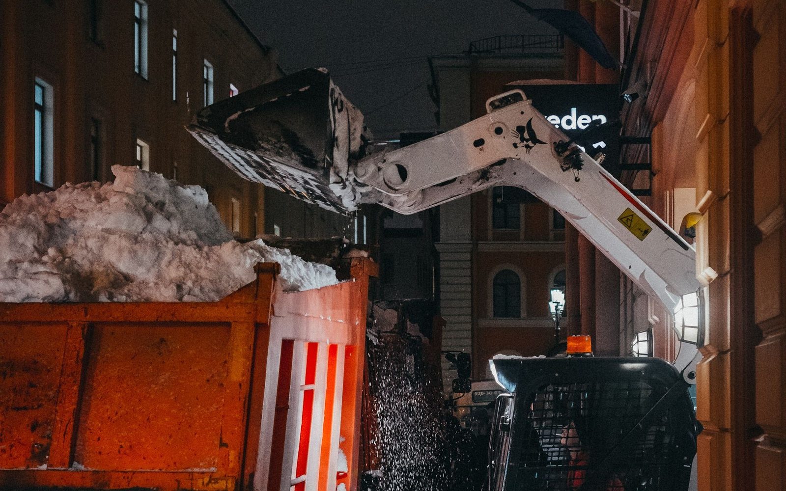 Waste container being loaded onto a truck at dusk